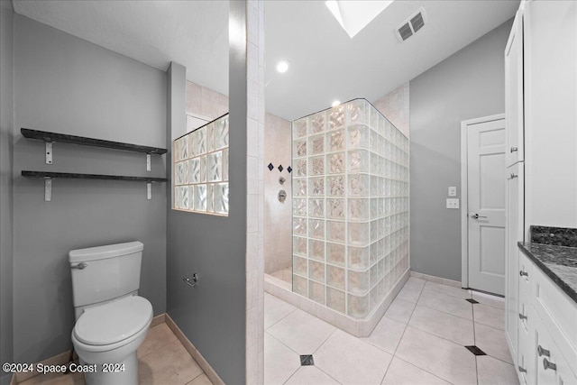 bathroom featuring vanity, toilet, tiled shower, and tile patterned flooring