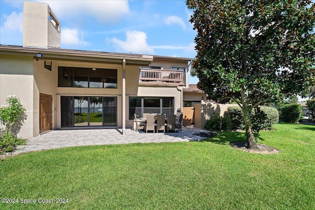 back of property with a lawn, a patio, and a balcony