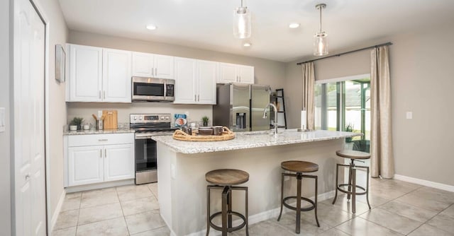 kitchen featuring sink, hanging light fixtures, a kitchen breakfast bar, stainless steel appliances, and a center island with sink