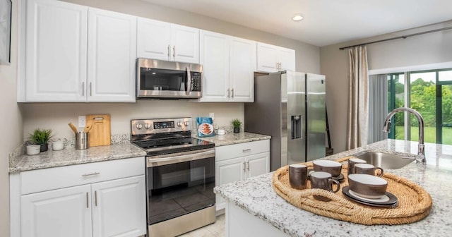 kitchen with light stone countertops, appliances with stainless steel finishes, sink, and white cabinets