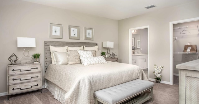 bedroom featuring ensuite bathroom, sink, dark colored carpet, a walk in closet, and a closet