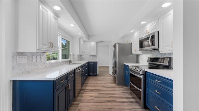 kitchen with blue cabinets, sink, wood-type flooring, appliances with stainless steel finishes, and white cabinets