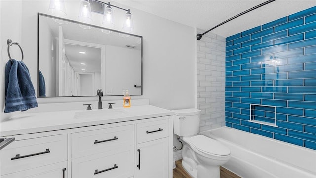 full bathroom featuring vanity, wood-type flooring, a textured ceiling, tiled shower / bath, and toilet