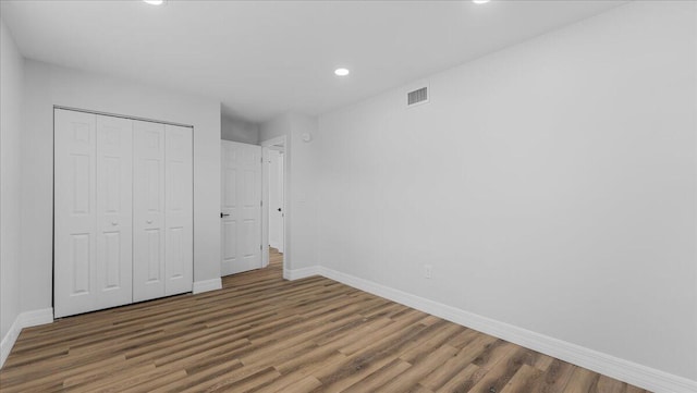 unfurnished bedroom with dark wood-type flooring and a closet