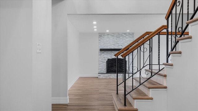 stairway featuring hardwood / wood-style flooring and a fireplace