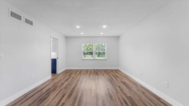 unfurnished room with dark wood-type flooring and a textured ceiling