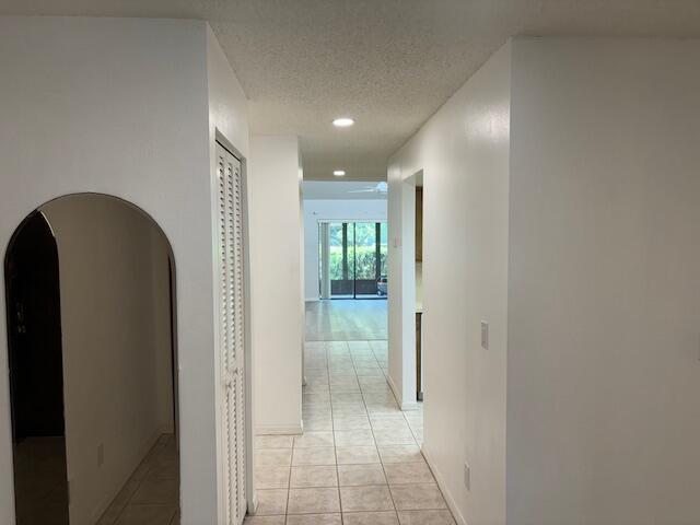 corridor featuring light tile patterned floors and a textured ceiling