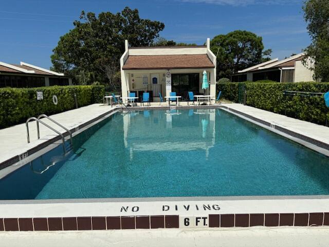 community pool featuring fence, a patio, and an outdoor structure