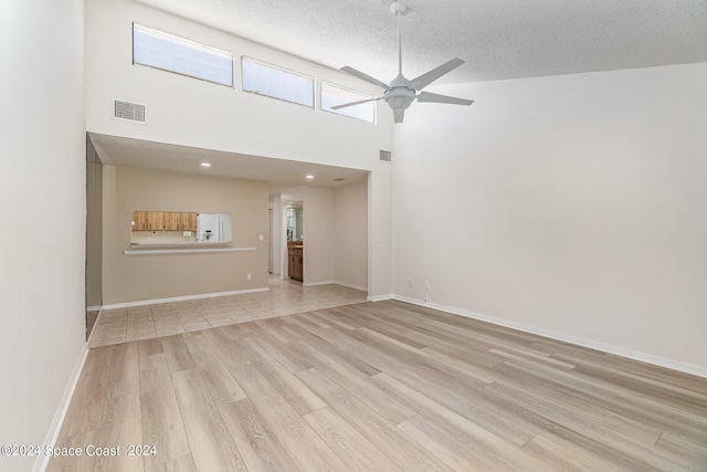 unfurnished living room featuring visible vents, baseboards, ceiling fan, a textured ceiling, and light wood-style floors