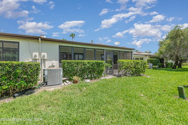 rear view of property featuring a lawn and central air condition unit