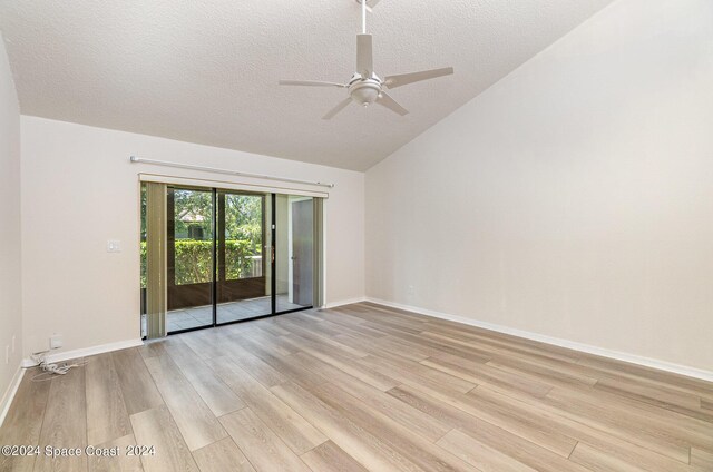 empty room with ceiling fan, vaulted ceiling, light hardwood / wood-style flooring, and a textured ceiling