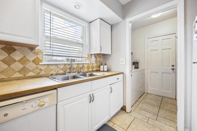 kitchen with washer and dryer, dishwasher, sink, white cabinets, and decorative backsplash