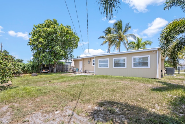 back of property featuring a yard and central AC