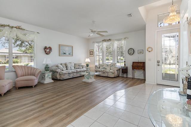 living room with light hardwood / wood-style floors, a wealth of natural light, and ceiling fan with notable chandelier