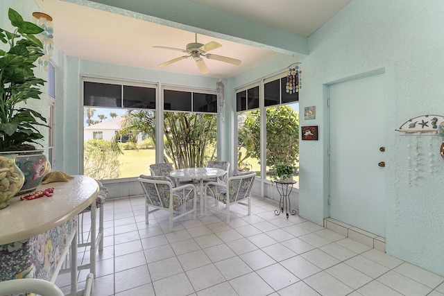 sunroom with ceiling fan, beamed ceiling, and a wealth of natural light