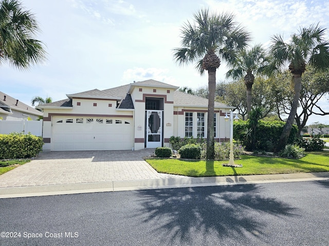 ranch-style house with stucco siding, fence, driveway, a front yard, and an attached garage