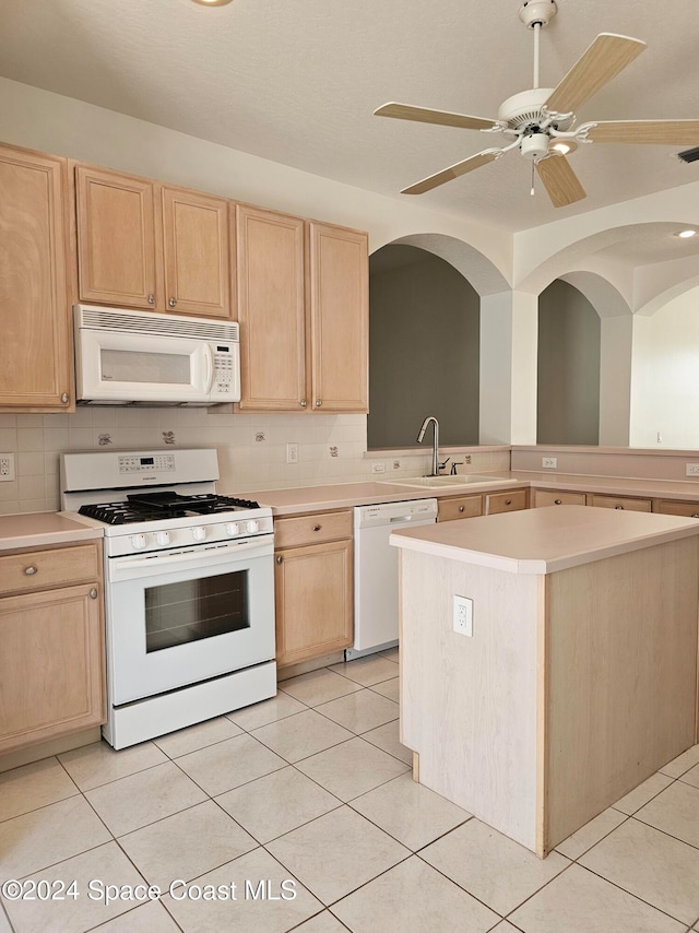 kitchen featuring ceiling fan, light tile patterned floors, a kitchen island, backsplash, and white appliances