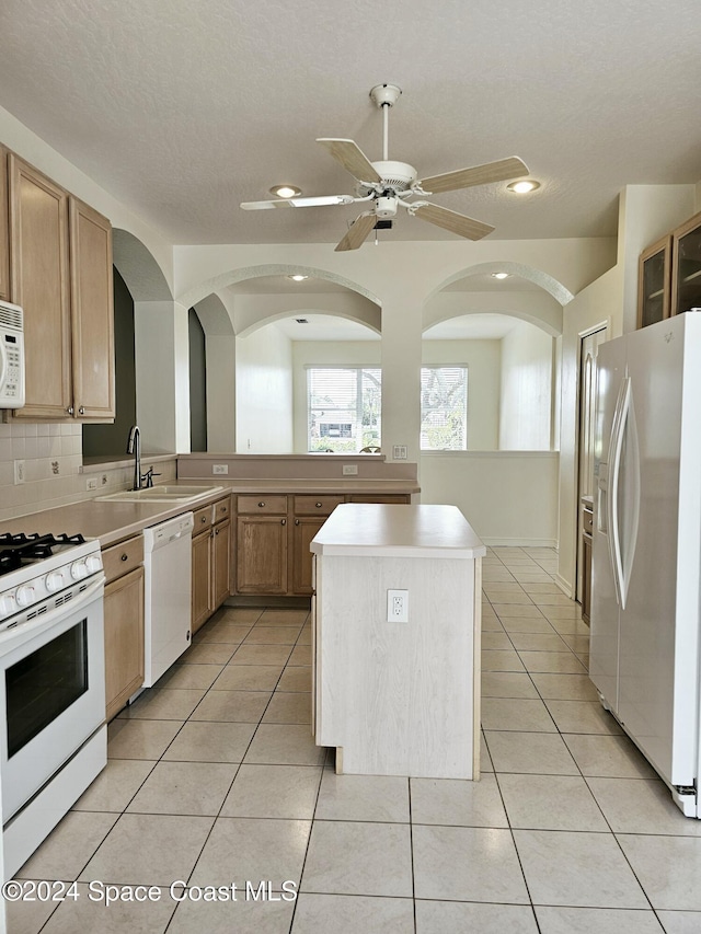 kitchen featuring light tile patterned flooring, white appliances, light countertops, and a sink