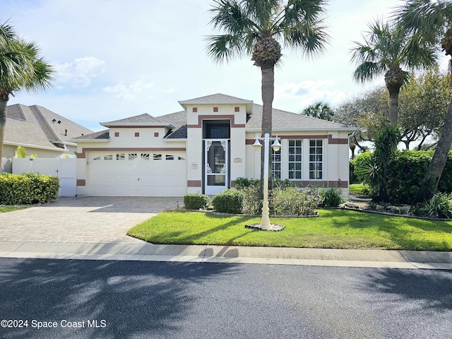 view of front of home featuring stucco siding, driveway, a front lawn, and a garage