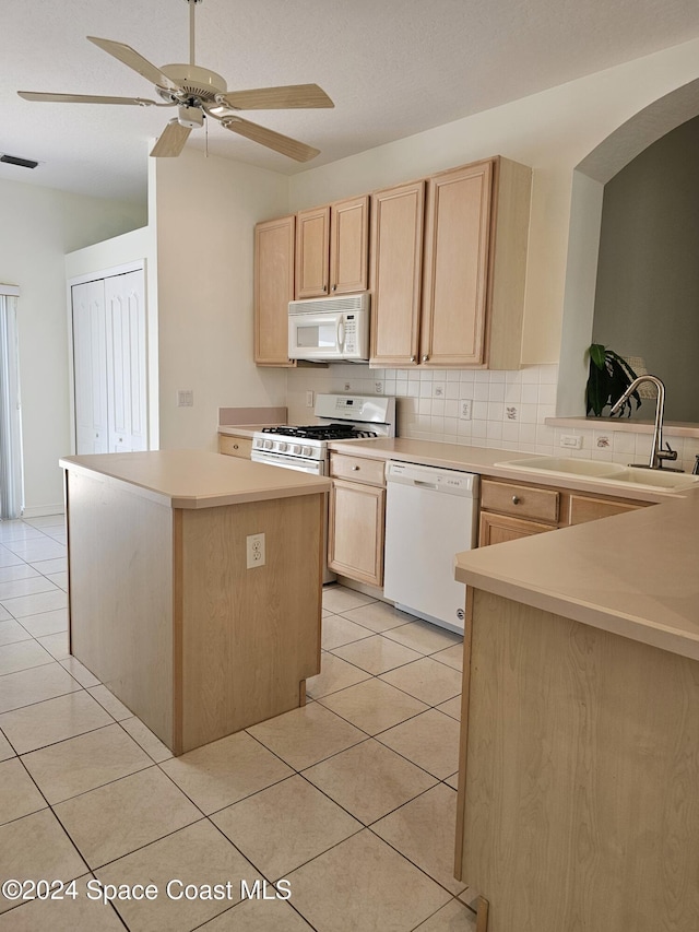kitchen featuring light brown cabinetry, a sink, visible vents, and white appliances