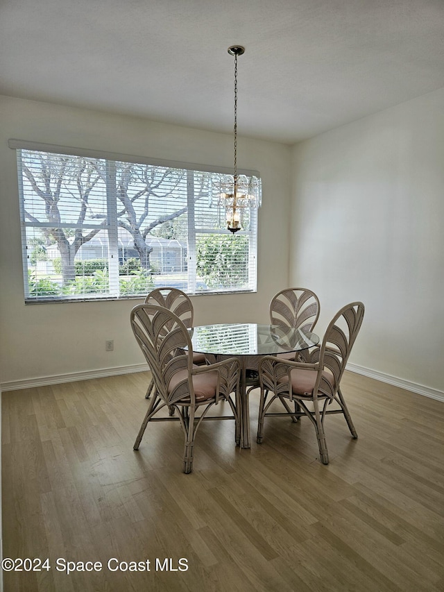 dining area featuring a notable chandelier, a wealth of natural light, wood finished floors, and baseboards