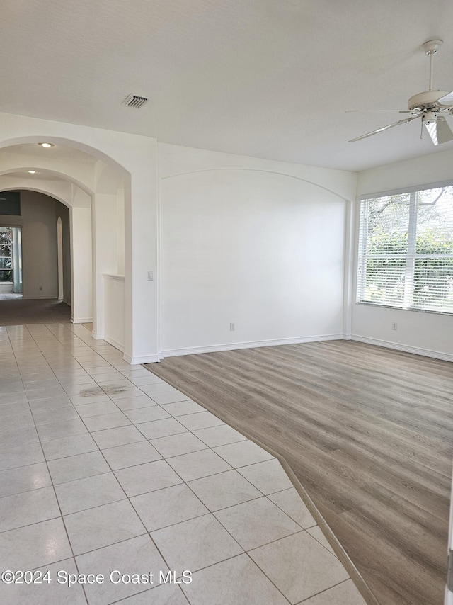 unfurnished room featuring visible vents, ceiling fan, baseboards, and arched walkways