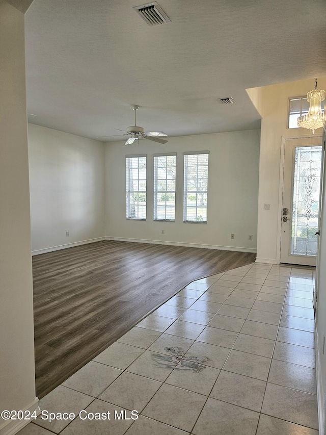 entryway with light tile patterned flooring, visible vents, baseboards, and ceiling fan with notable chandelier