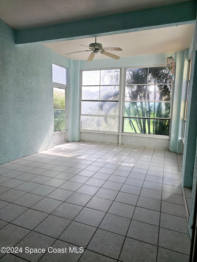 unfurnished sunroom with beamed ceiling and ceiling fan