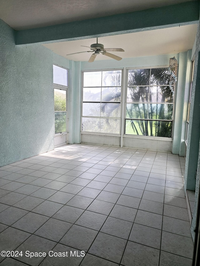 unfurnished room featuring tile patterned flooring, a ceiling fan, and a textured wall