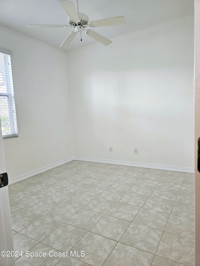 empty room with ceiling fan and light tile patterned floors