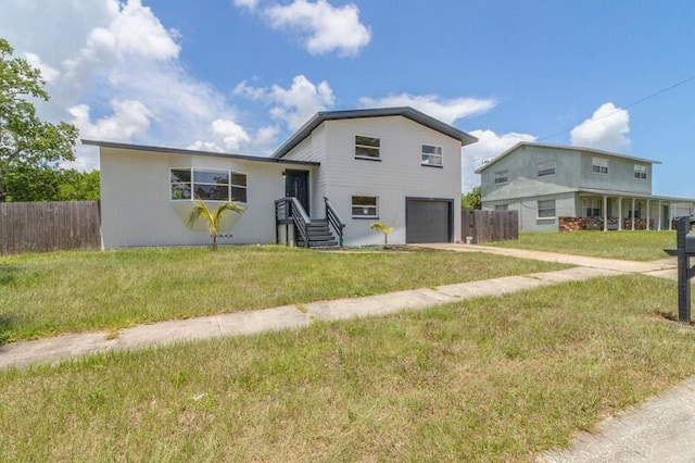 split level home with a garage, a front yard, fence, and driveway