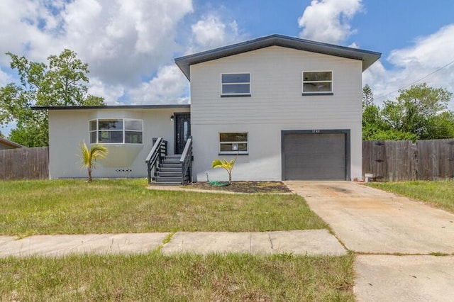 view of front facade featuring a front yard, fence, driveway, and an attached garage