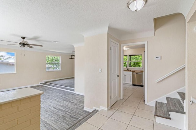 interior space with light tile patterned floors, a textured ceiling, stairway, and a ceiling fan