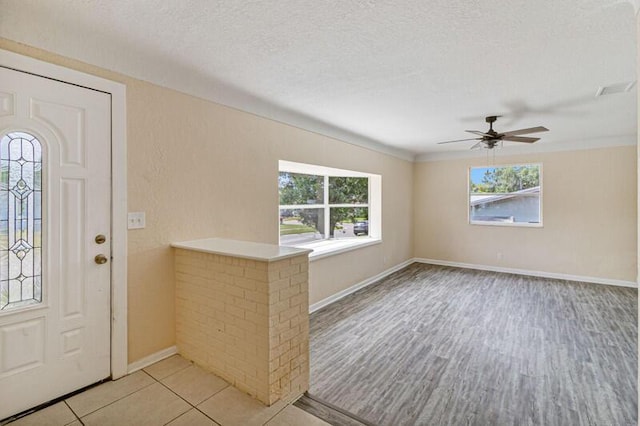 entrance foyer featuring a textured ceiling, visible vents, a ceiling fan, baseboards, and light wood-type flooring