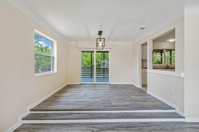 empty room featuring a healthy amount of sunlight, visible vents, and wood finished floors