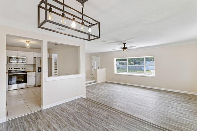 spare room with light wood-type flooring, baseboards, visible vents, and a ceiling fan