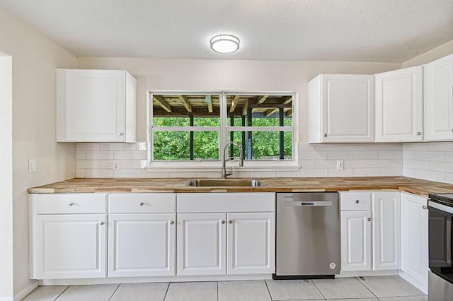 kitchen with appliances with stainless steel finishes, butcher block counters, white cabinets, and a sink