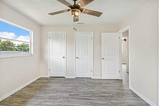 unfurnished bedroom with baseboards, a ceiling fan, visible vents, and light wood-style floors