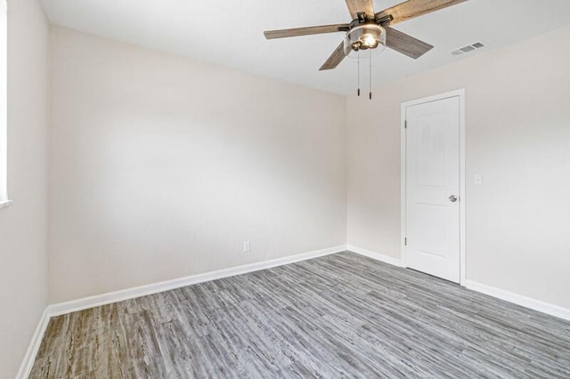 unfurnished room with baseboards, visible vents, and wood finished floors