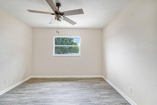 empty room with light wood-style flooring, baseboards, ceiling fan, and a textured ceiling