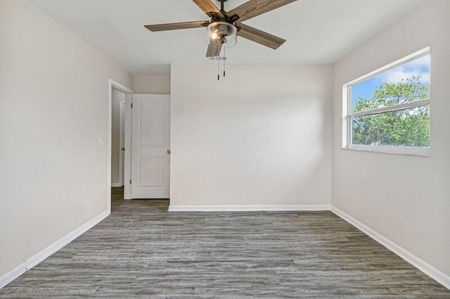 unfurnished room featuring dark wood finished floors, a ceiling fan, and baseboards