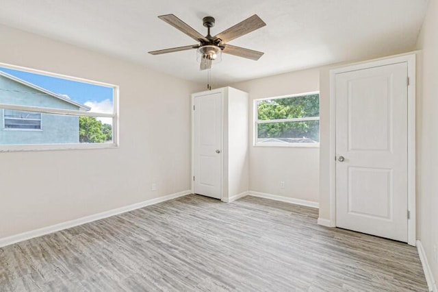 unfurnished bedroom with ceiling fan, light wood-style flooring, and baseboards