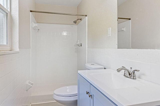 full bathroom featuring a shower stall, tile walls, toilet, and vanity