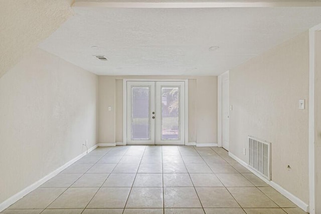 spare room with baseboards, visible vents, a textured ceiling, french doors, and light tile patterned flooring