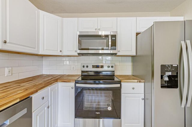 kitchen featuring stainless steel appliances, tasteful backsplash, wooden counters, and white cabinetry