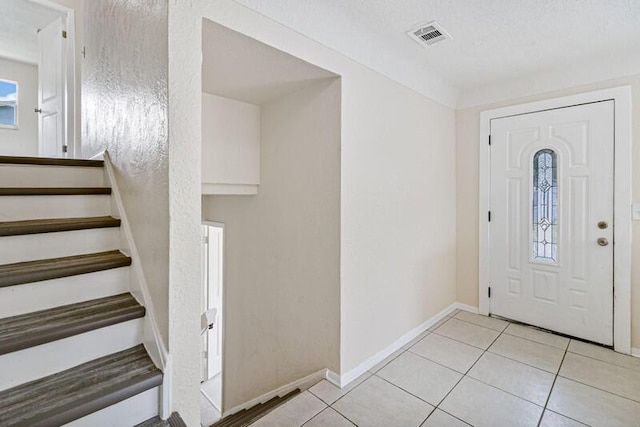 entrance foyer with baseboards, stairs, visible vents, and light tile patterned flooring