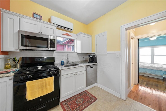 kitchen featuring sink, white cabinetry, a wall mounted AC, stainless steel appliances, and decorative backsplash