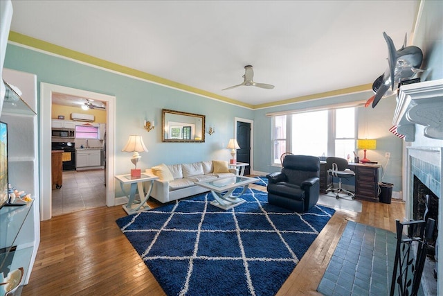 living room featuring dark wood-type flooring, ceiling fan, sink, and a tile fireplace