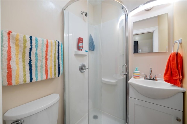 bathroom with vanity, a shower with door, and toilet