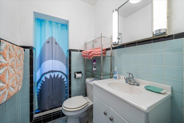 bathroom featuring vanity, toilet, and tile walls